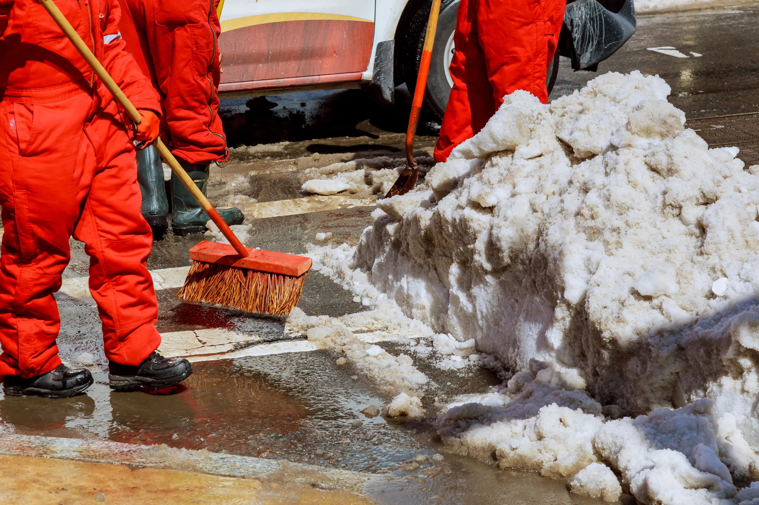 Workers sweep snow from road in winter. Cleaning road from snow storm